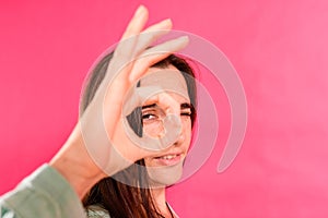 Young woman looks at you through her hands