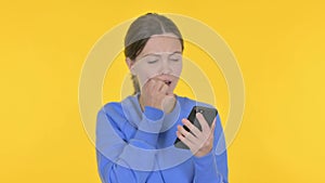 Young Woman Loss on Smartphone on Yellow Background