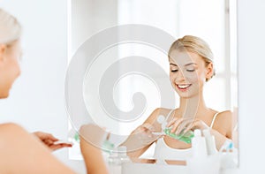 Young woman with lotion washing face at bathroom