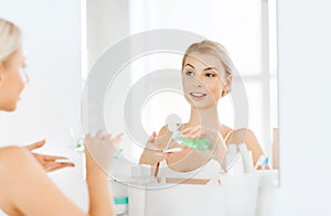 Young woman with lotion washing face at bathroom