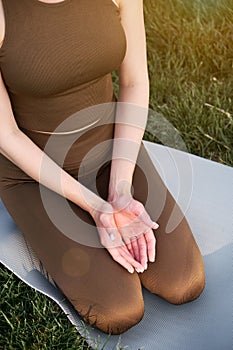 Young woman in lotus pose sitting on green grass. Concept of calm and meditation
