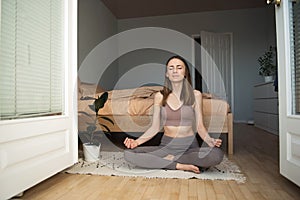 Young woman in the lotus position meditating at home