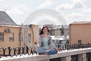 Young woman in a lotus position on the parapet photo