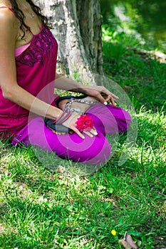 Young woman in lotus posture on grass in nature meditate lower b