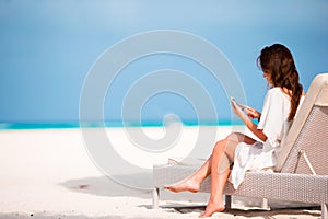 Young woman on lounger with mobile phone at the beach