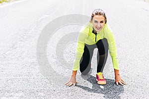 A young woman in low start position going to run