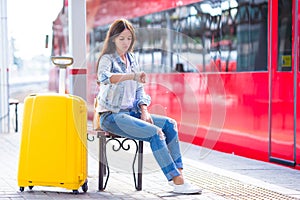 Young woman with luggage on train platform waiting