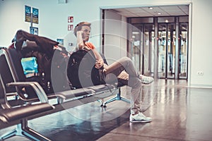 Young woman with luggage waiting in the airport hall her plane