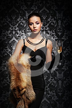 A young woman in luxurious clothes holding champagne