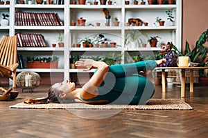 Young woman lying on the back with his knees doing twisting exercise at home