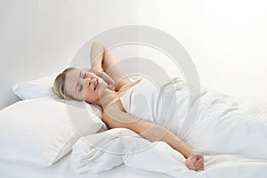 Young woman lying in the bed. Beautiful blond sleeping girl. Morning in the bedroom, daylight from the window. Health