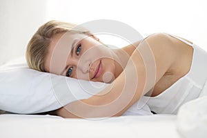 Young woman lying in the bed. Beautiful blond sleeping girl. Morning in the bedroom, daylight from the window. Health