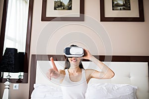 Young woman lying on bed, using Vr Glasses at home