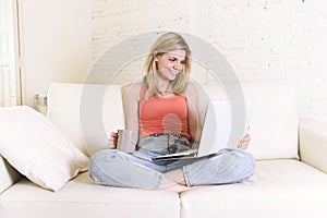 Young woman lying comfortable on home sofa using internet in laptop computer smiling happy