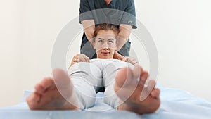 Young woman lying on a couch - the massagist pressing on her shoulders