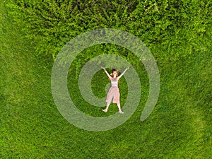Young woman lying down in the middle of a field and relaxing, drone photo
