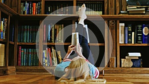 Young woman lying down reading a book. Is lying in the library