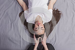 Young woman lying while enjoying the acupressure techniques of traditional Thai massage on her face at spa and wellness center