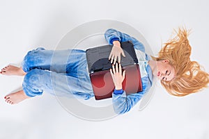 Young woman lying on the floor in his pajamas with a laptop.