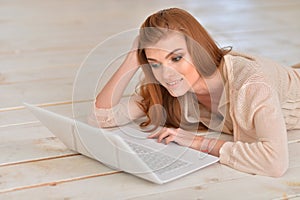 Young woman lying on floor with laptop