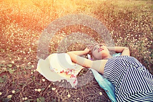 Young woman lying in grass nearing her hat look into the s