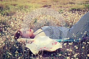 Young woman lying in grass nearing her hat look into the sk