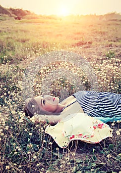 Young woman lying in grass nearing her hat look into the sk