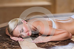 Young woman lying on hammam table in turkish bath