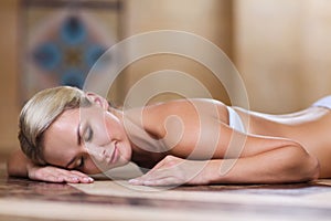 Young woman lying on hammam table in turkish bath