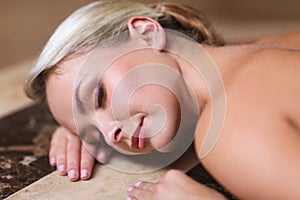 Young woman lying on hammam table in turkish bath