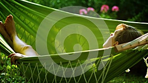 Young woman lying on hammock on backyard.