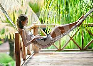 Young woman lying in a hammock with laptop
