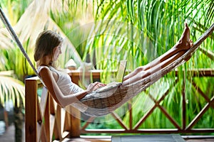 Young woman lying in a hammock with laptop