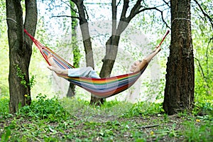 Young woman lying in hammock and relaxing outdoors