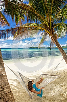 Young woman lying in a hammock on a tropical beach