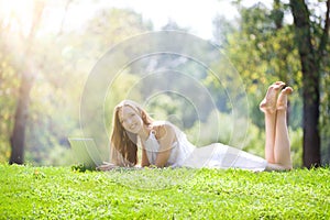 Young Woman Lying with Laptop on the Beautiful Green Meadow