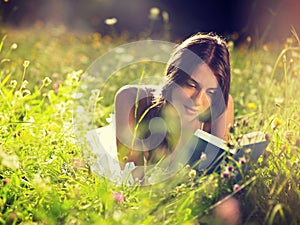 Young woman lying in meadow reading book