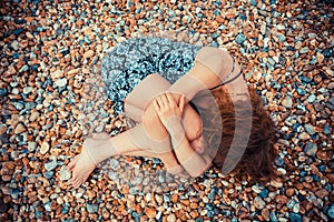 Young woman lying on a pebble beach