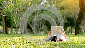 Young woman lying and reading her favorite book on the grass.Concept of recreation, education and study , curiosity, leisure time