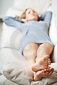 Young woman lying on sofa, focus on her feet