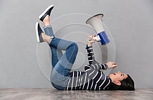 Young woman lying and speaking in megaphone