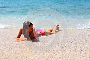 Young woman lying on stomach on the beach