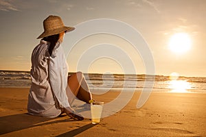 Young woman lying in straw hat in sunglasses on beach