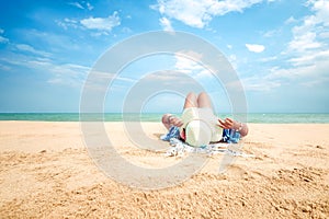 Young woman lying on a tropical beach, relax with hat.