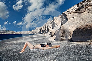 Young woman lying at Vlychada beach in Santorini, Greece