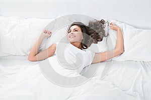 Young woman lying on the white linen in bed