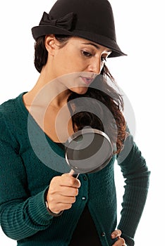 Young woman with magnifier glass and hat looking