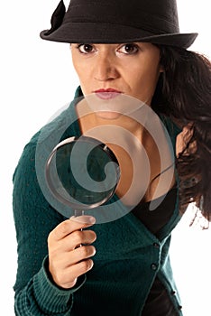 Young woman with magnifier glass and hat looking