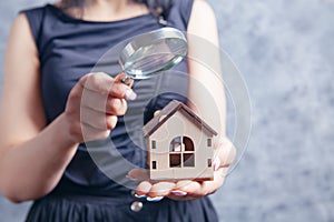 Young woman with a magnifying glass looks at the house