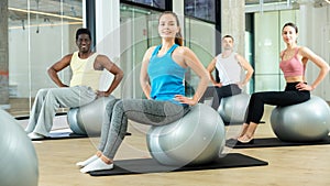 Young woman exercising with pilates ball during group class photo